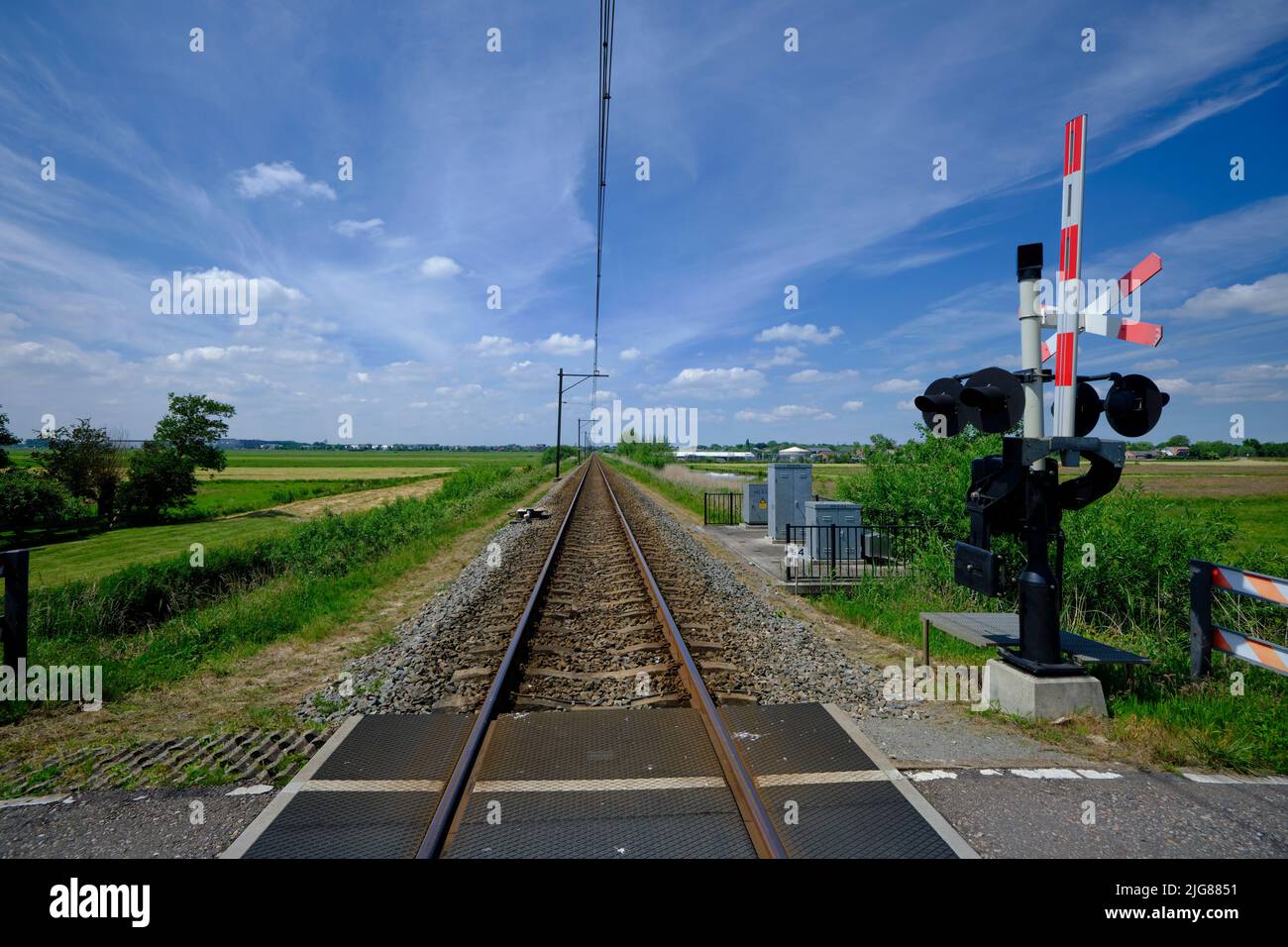 Guarded railroad crossing with open barriers, red warning light and cross of Saint Andrew in the NEtherlands. Stock Photo
