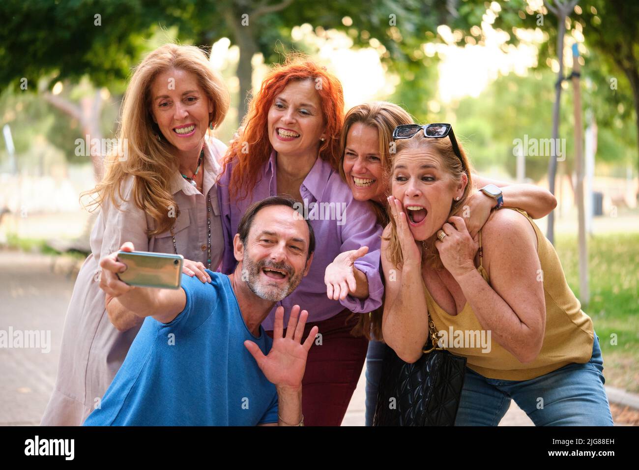 Five mature adults taking a selfie and having fun in a park. Stock Photo