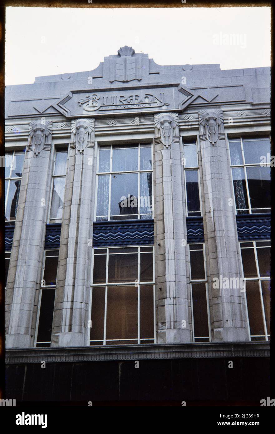 Burton, 22-24 Old Market, Halifax, Calderdale, 1970s-1980s. Looking up at the centre of the west, Princess Street elevation of the Burton store at 22-24 Old Market, showing the central relief carving bearing the company's logo. Foundation stones were laid at the Old Market store by Arnold James Burton, Raymond Montague Burton and Stanley Howard Burton in 1932. The premises were later occupied by businesses including McDonald's. Stylised elephant heads, shown crowning pilasters between the first and second floor windows, are one a number of motifs used in the design of Burton stores. They featu Stock Photo