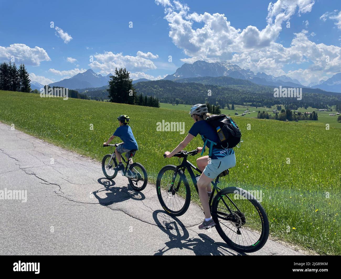 Mother with child cycling, view over mogul meadows to Wetterstein mountains, woman, child, nature, mountains, blue sky, activity, Tonihof, Alpenwelt Karwendel, Mittenwald, Upper Bavaria, Germany Stock Photo