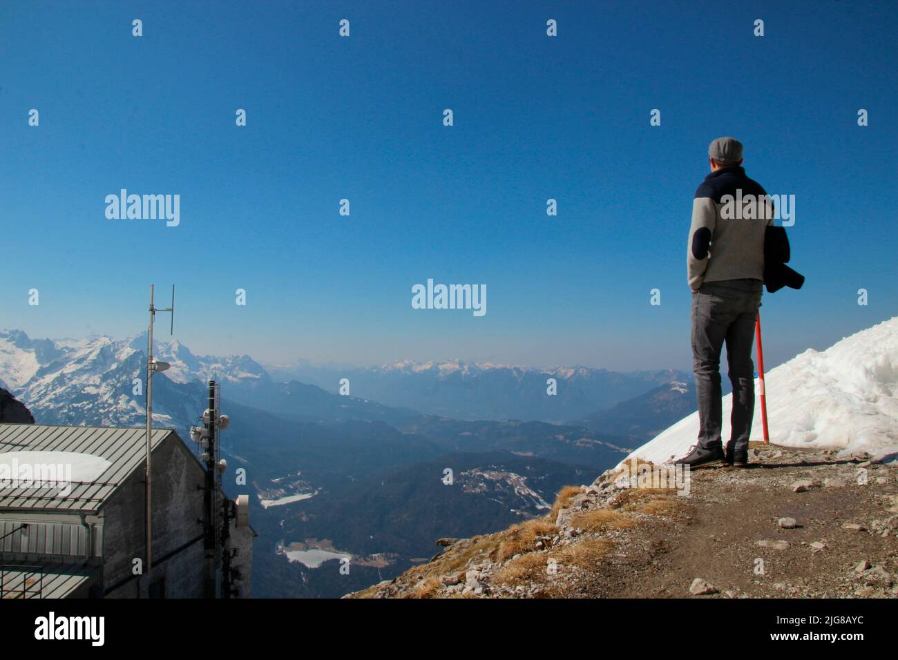 Young man, Karwendel mountain station, view from Karwendel, looking towards Wetterstein mountains, Mittenwald in the foreground, against blue sky, Stock Photo
