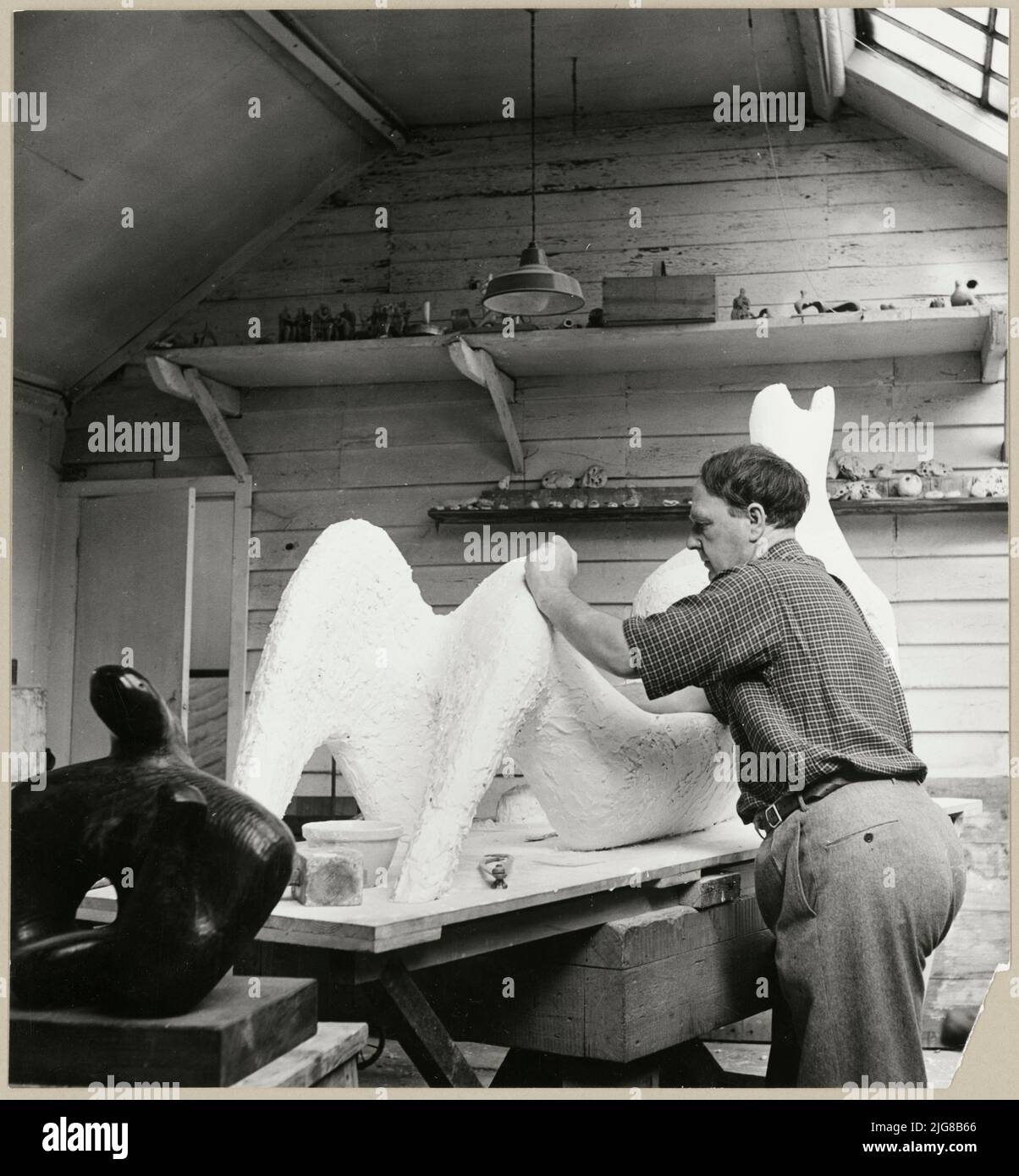 Hoglands, Perry Green, Much Hadham, East Hertfordshire, Hertfordshire, 03-10-1950. Henry Moore in his studio at Perry Green working on his sculpture 'Reclining Figure', commissioned by the Festival of Britain 1951 for the South Bank Exhibition, London. The original caption reads: &quot;Henry Moore in his studio working on his new sculpture commissioned by the Festival of Britain 1951 for the South Bank Exhibition, London.&quot; The final sculpture was created in bronze and had a surface decoration of thin string &quot;to define the form&quot;, which Moore described as &quot;[giving] the shape Stock Photo