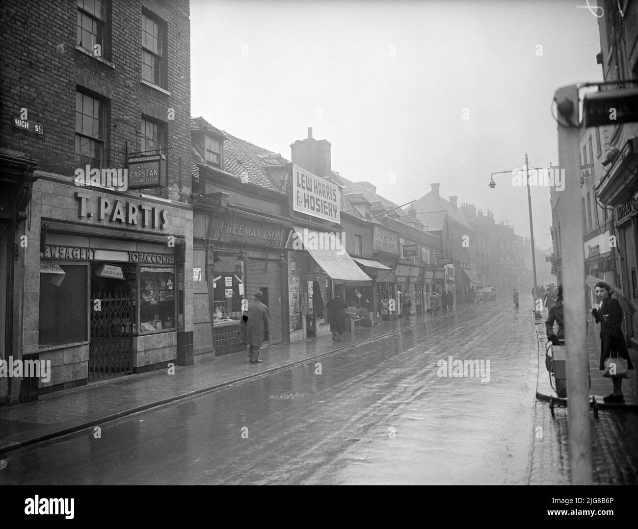 High Street, Chatham, Medway, 1942. View from the north-west showing terraced shops on the north side of the High Street, with number 277 in the foreground. The premises of T Partis, shown in this photograph as a newsagent and tobacconist, were at 277 High Street. This building, which still stands, is now (2021) occupied by a barber's shop. The adjoining buildings with dormer windows have been demolished and replaced with modern buildings, but the shops in the background of the picture are also still standing. Stock Photo