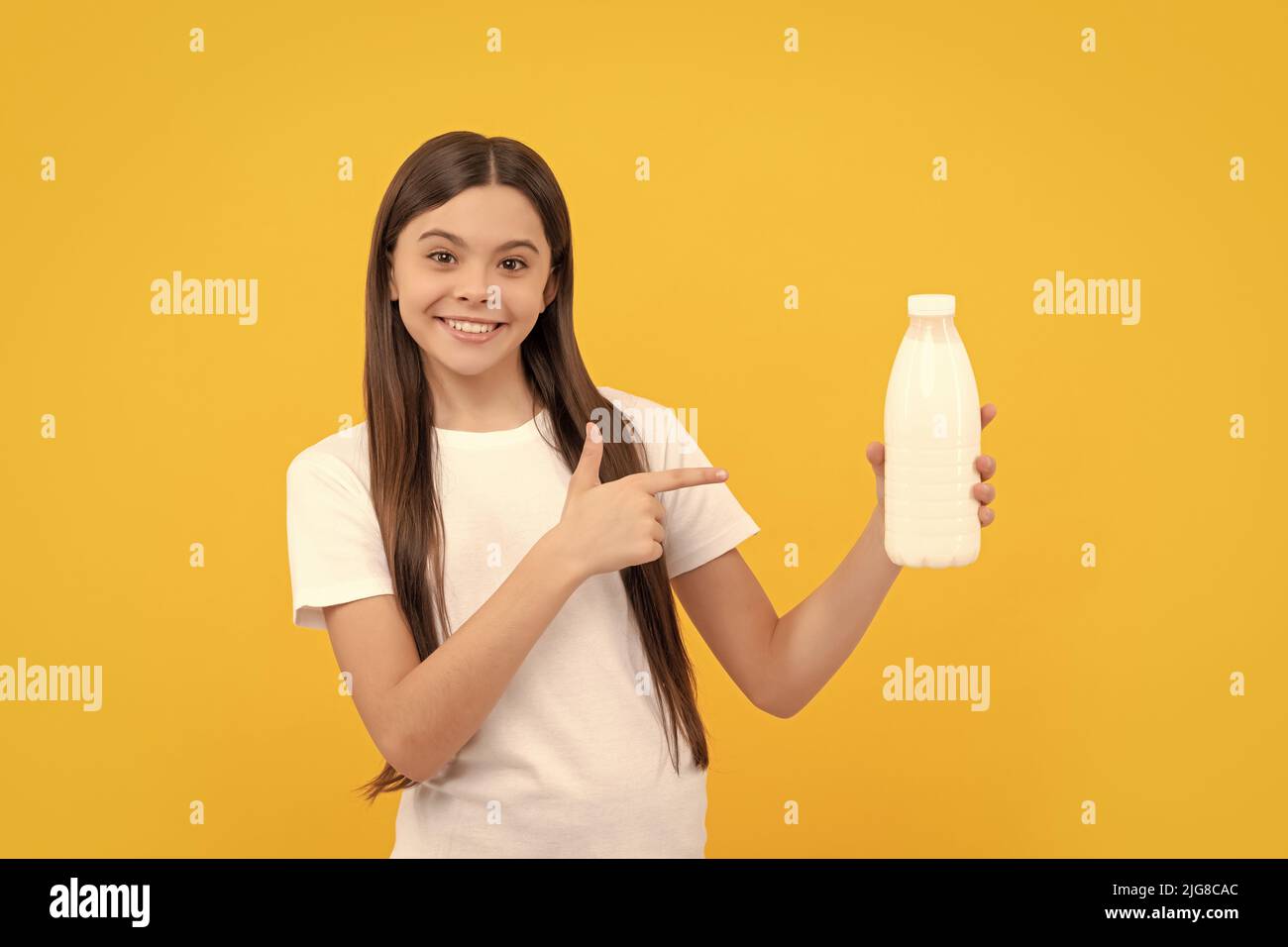 happy child pointing finger on dairy beverage product. teen girl going to drink milk. Stock Photo