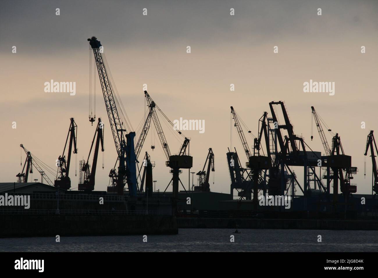 A silhouette of dock cranes against a cloudy sky Stock Photo - Alamy
