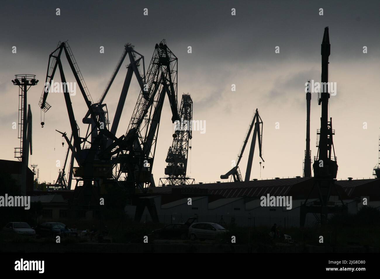 A silhouette of dock cranes against a cloudy sky Stock Photo - Alamy