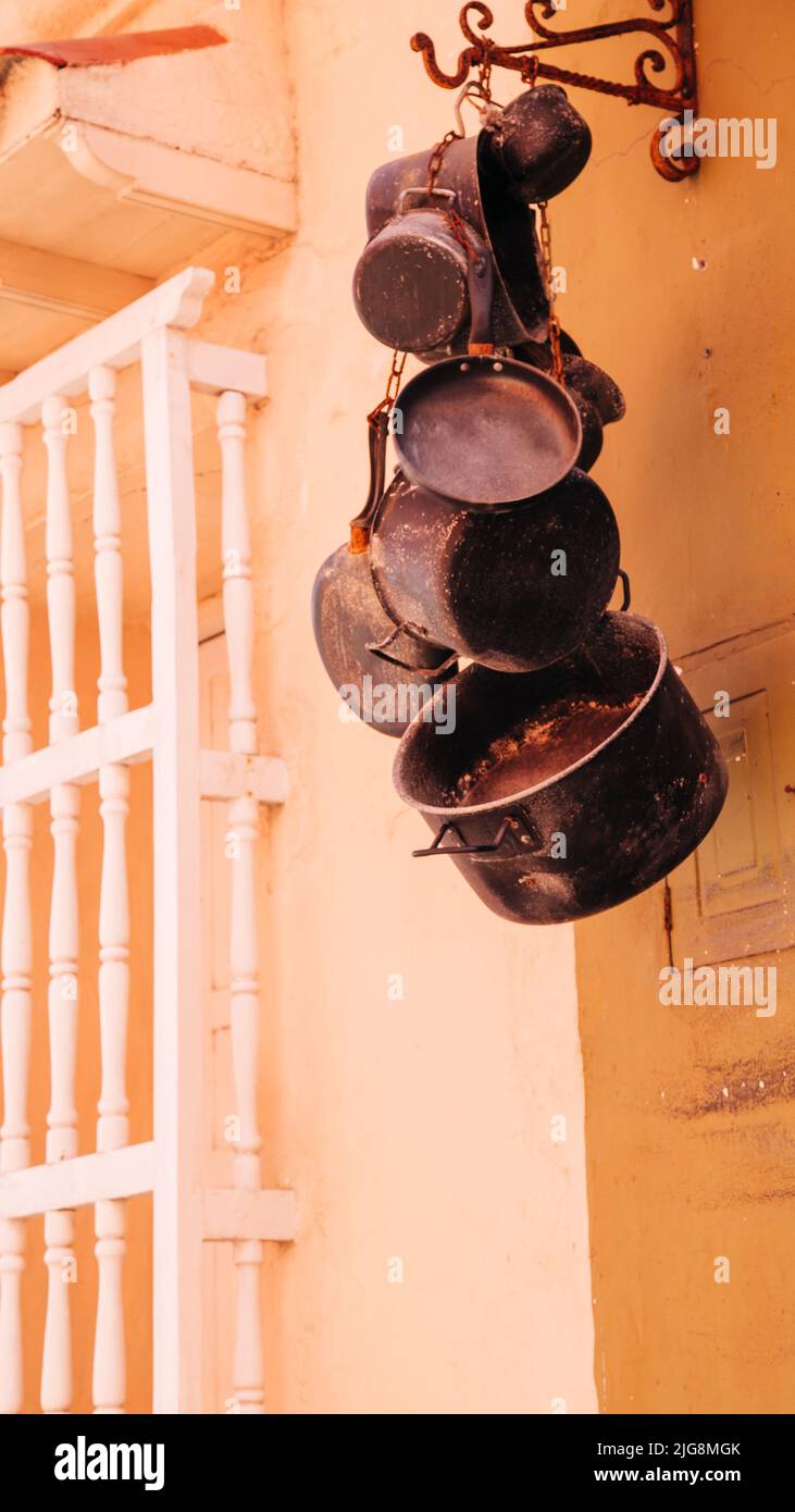 A vertical shot of a bunch of rusty pots and pans hanging on a wall