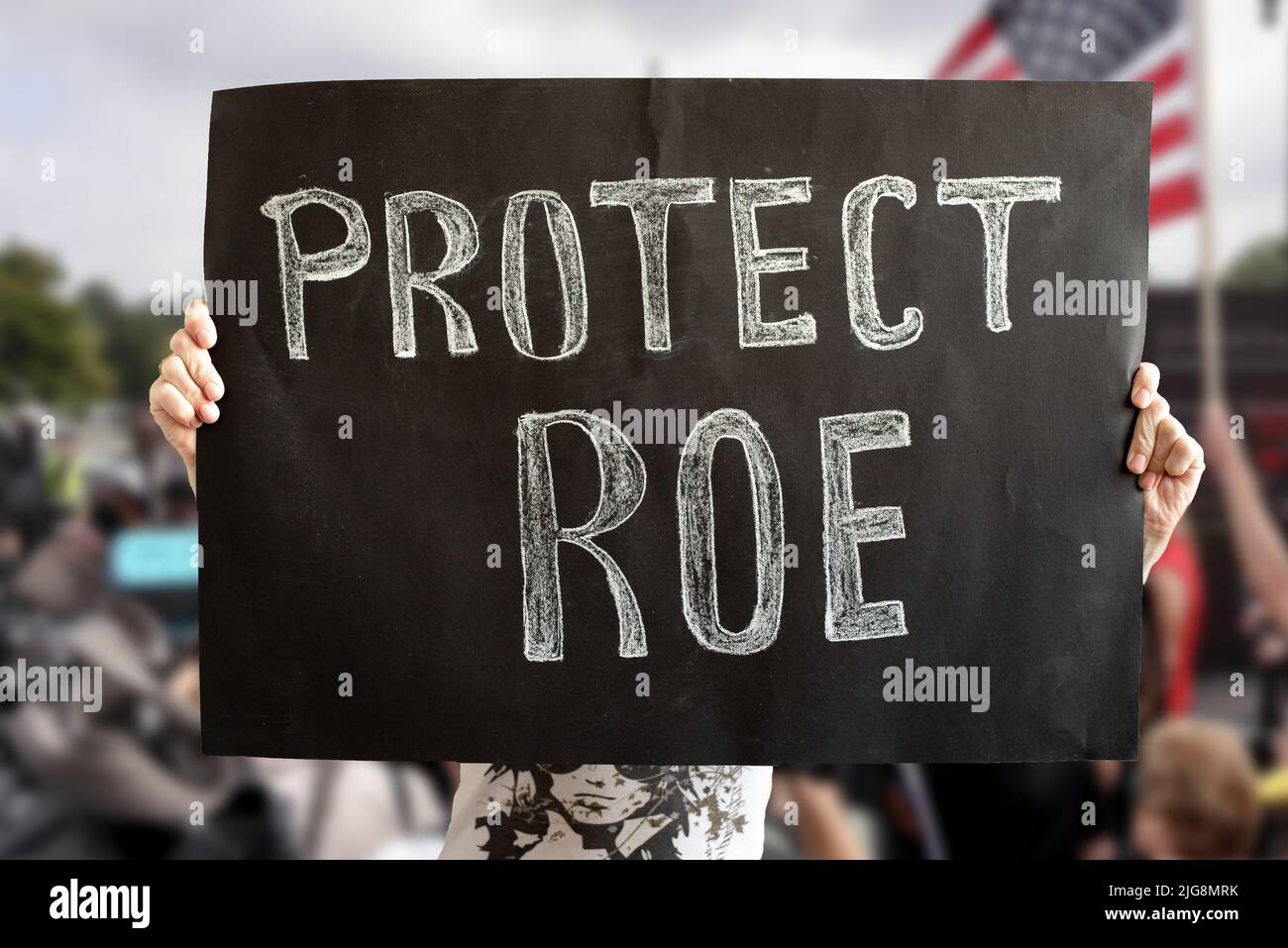 A woman's hands hold a Protect ROE banner. a woman stands up for her rights with a banner at a rally. The concept of protests in the United States. Fi Stock Photo