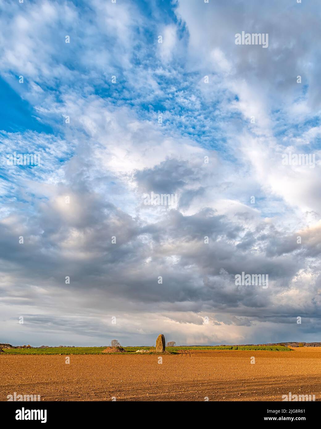 A single standing stone in the Swedish countryside against a dramatic cloudy sky Stock Photo
