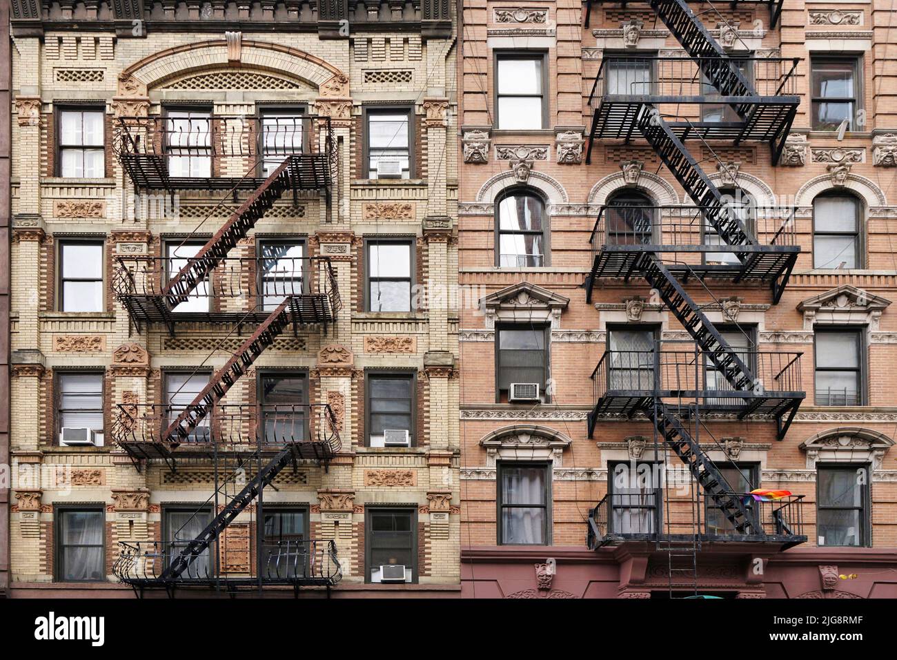 Old fashioned Manhattan apartment building facade with ornate decorative stone carving and external fire escape ladders Stock Photo