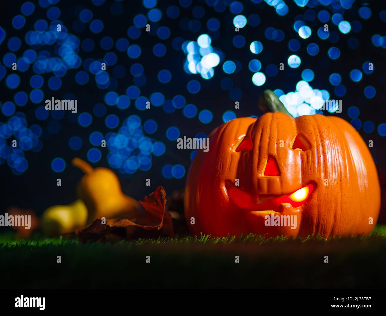Against the backdrop of a blue starry sky Halloween composition. A large orange pumpkin with a carved face, a smile, illuminated from the inside on a Stock Photo
