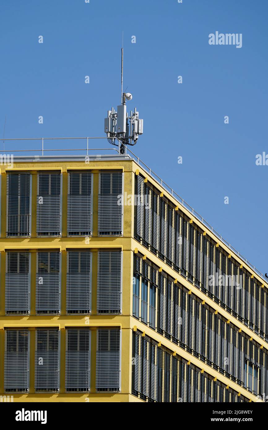 Germany, Bavaria, Munich, office building, yellow facade, sun blinds, radio antenna Stock Photo