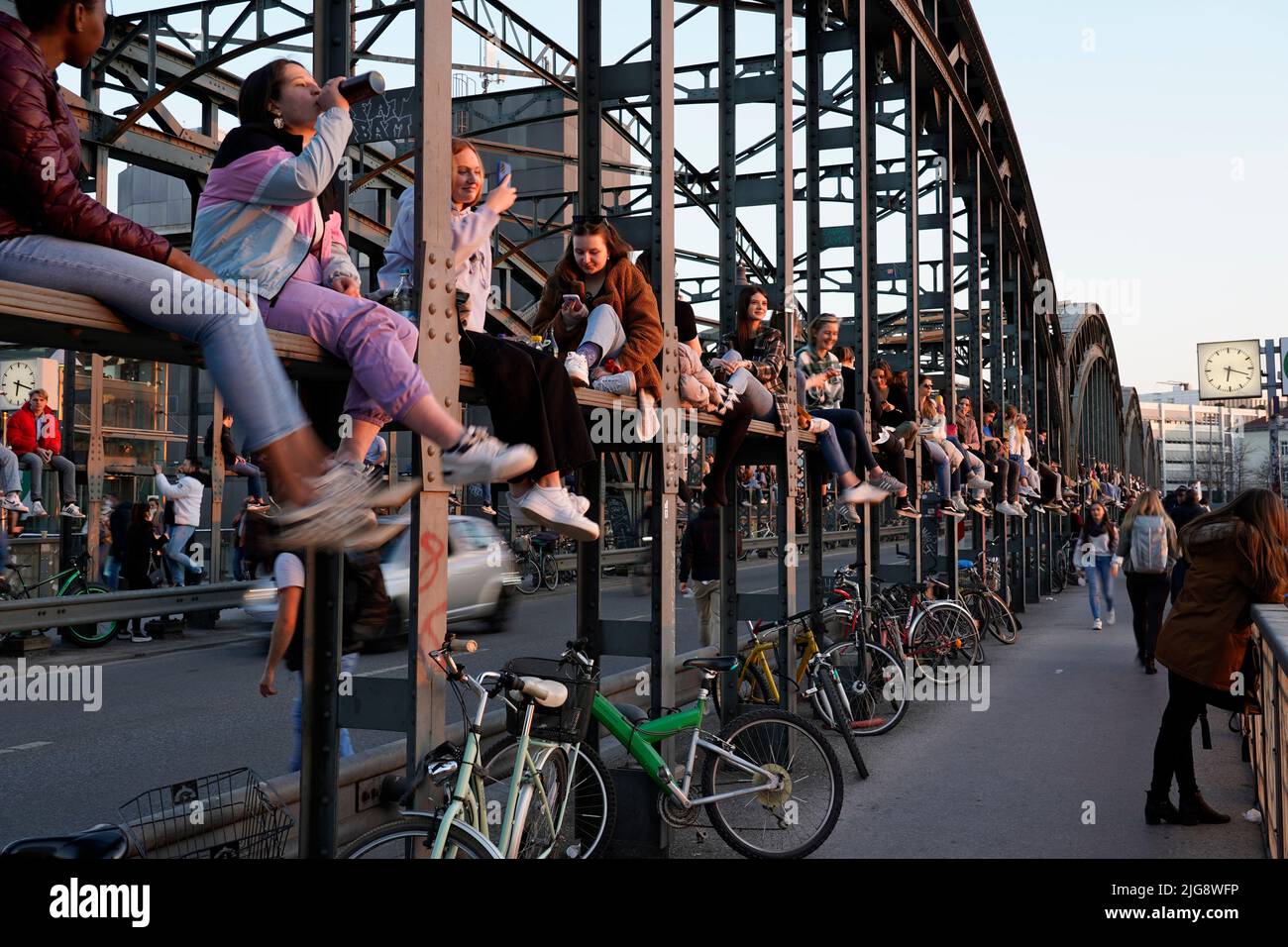 Germany, Bavaria, Munich, Hackerbrücke, young people sit on the bridge construction and enjoy the sunset Stock Photo