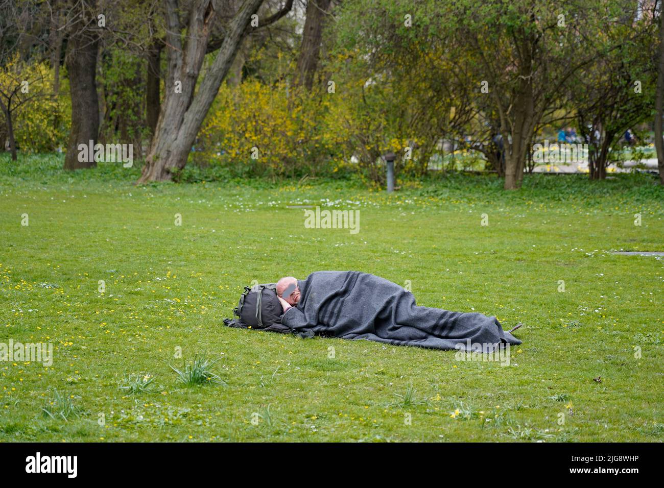 Germany, Bavaria, Munich, Old Botanical Garden, homeless man, sleeping on a meadow Stock Photo