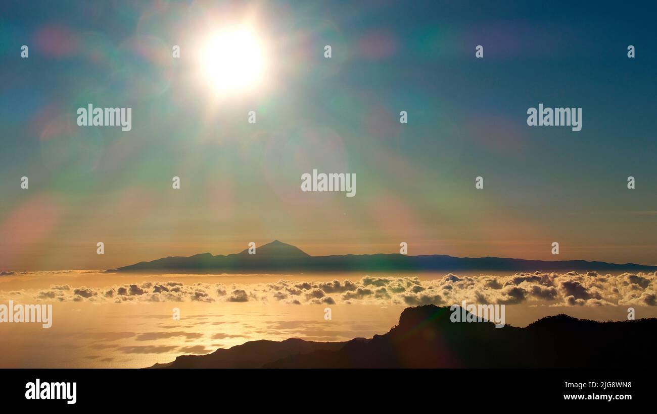 Spain, Canary Islands, Gran Canaria, Massif Central, sunset, sun as a star over the Teide, sea backlit, clouds Over the sea, blue sky Stock Photo