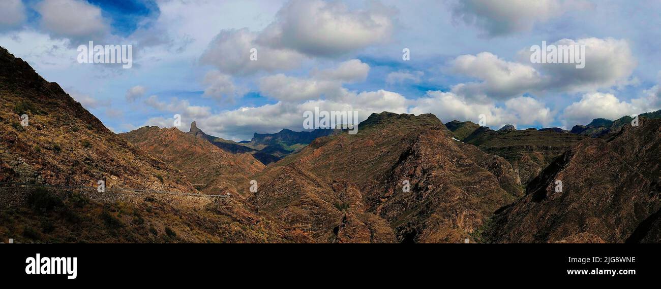 Spain, Canary Islands, Gran Canaria, Massif Central, Barranco de la Aldea, View over the Barranco de la Aldea to the north to the Roque Bentayga, Blue sky with grey white clouds Stock Photo