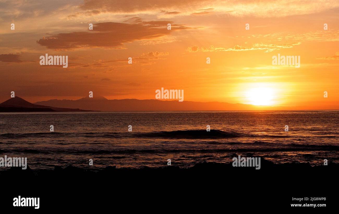 Spain, Canary Islands, Gran Canaria, Las Palmas, Playa de las Canteras, sunset, grey-white clouds, sky orange, hilly coastline Stock Photo