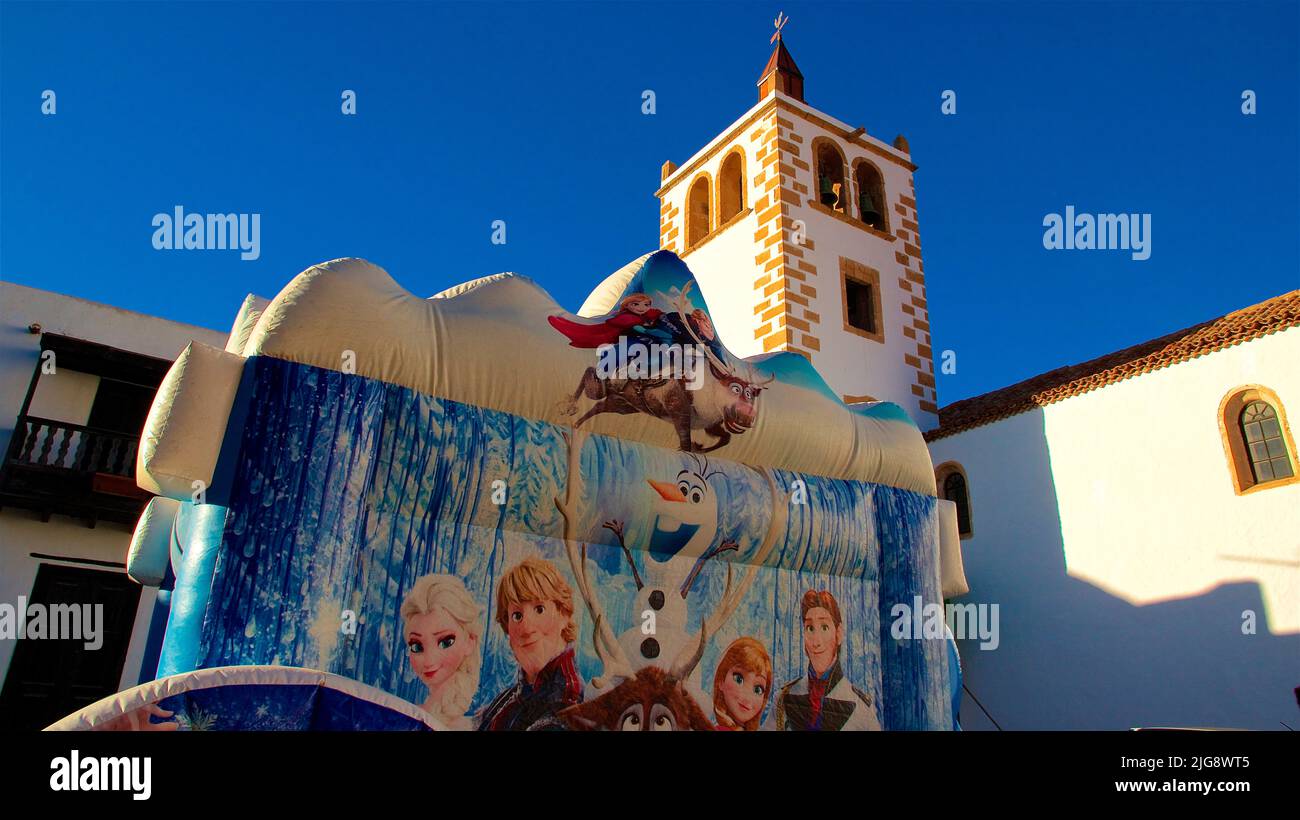 Spain, Canary Islands, Fuerteventura, Betancuria, old capital, old town, Iglesia de Santa Maria de Betancuria, bouncy castle, ice queen, blue cloudless sky Stock Photo