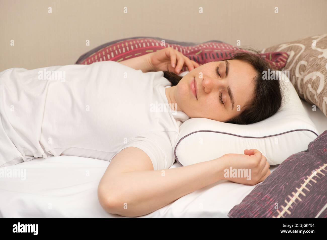 A woman lies on an orthopedic pillow, choosing it among other different