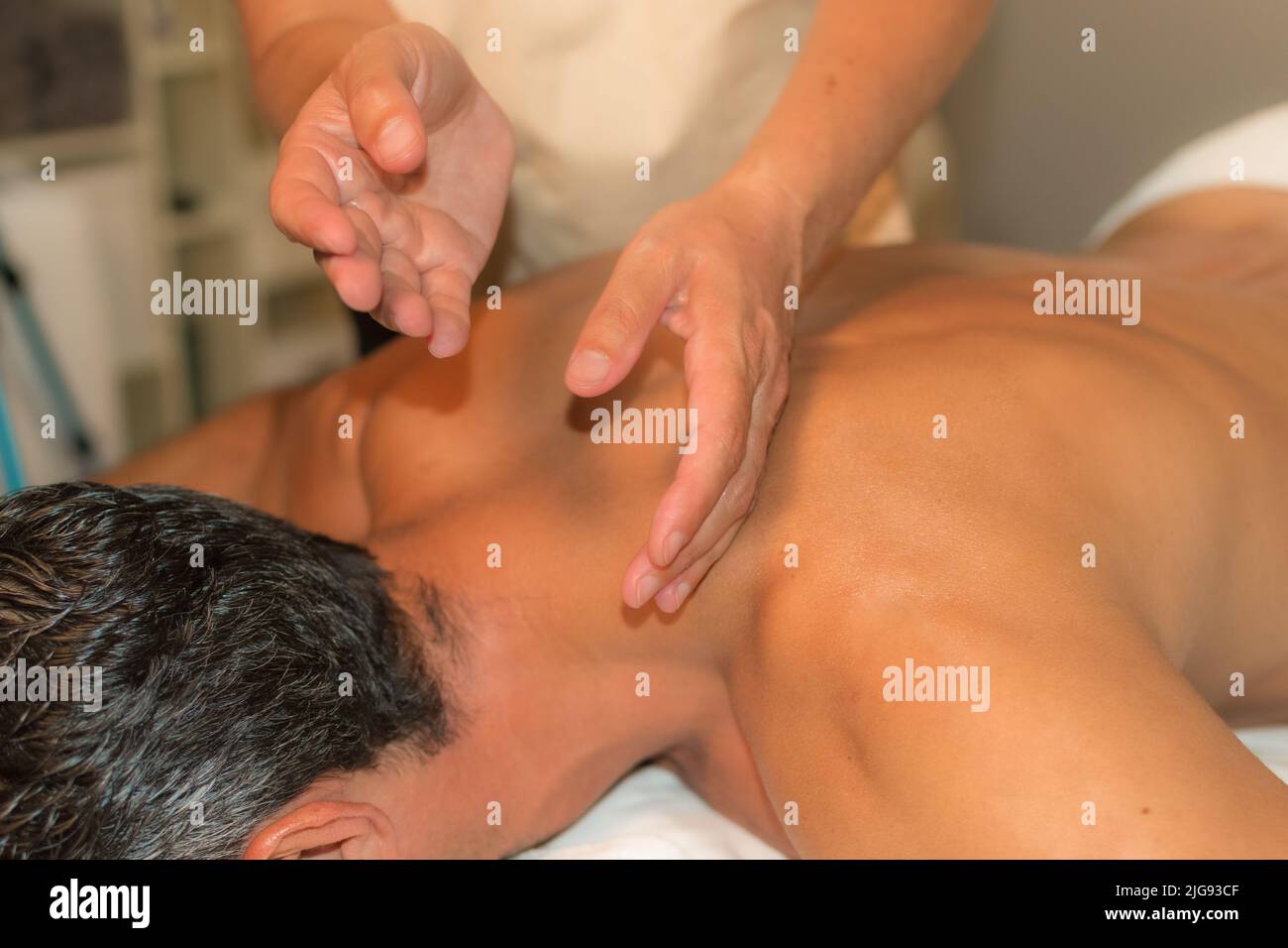 man receiving therapeutic massage by percussion on the upper back area Stock Photo