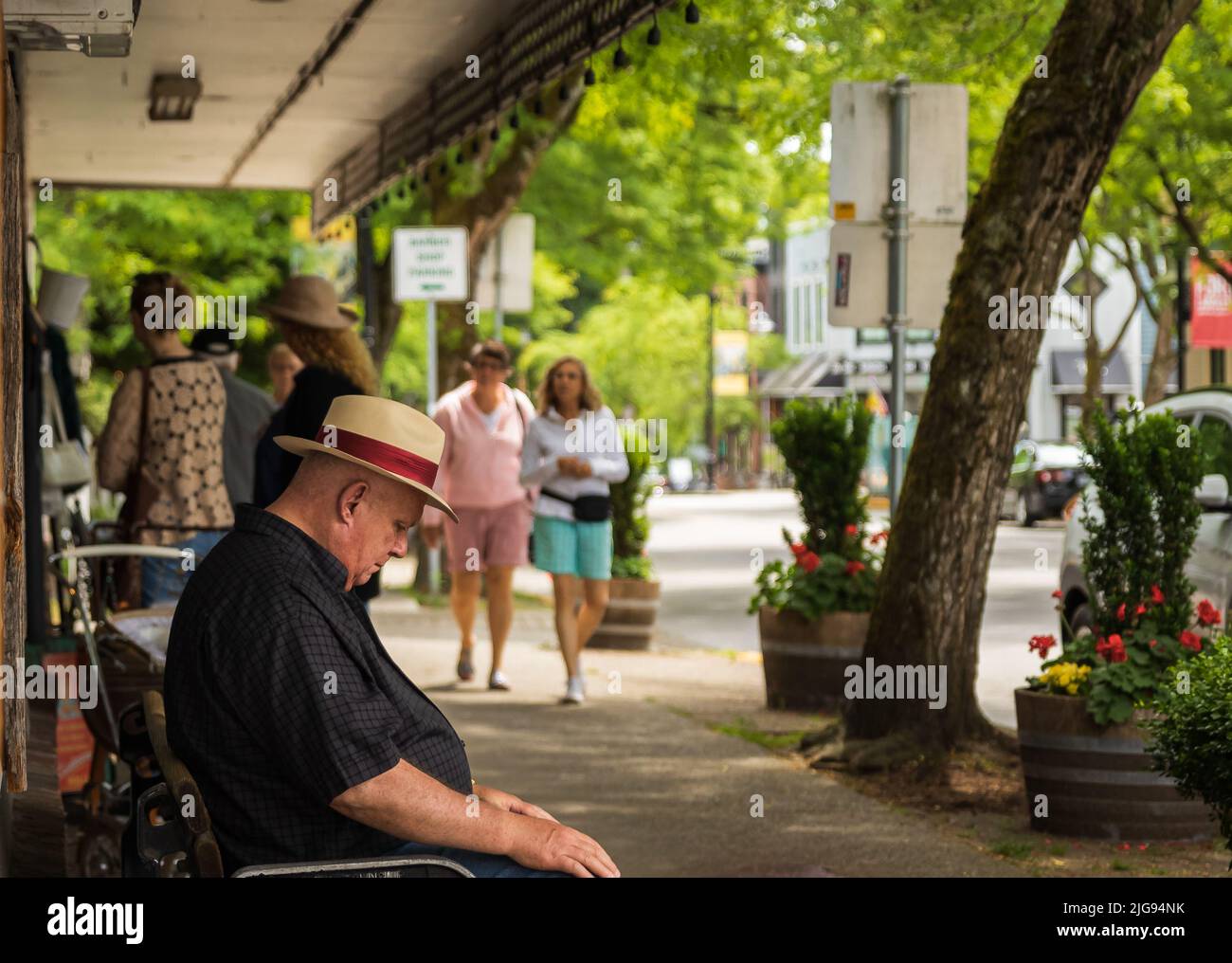 Sad old man sitting on a street bench. Lonely sad miss widower wear hat on city park outside at summer day. Street photo, selective focus-July 5,2022- Stock Photo