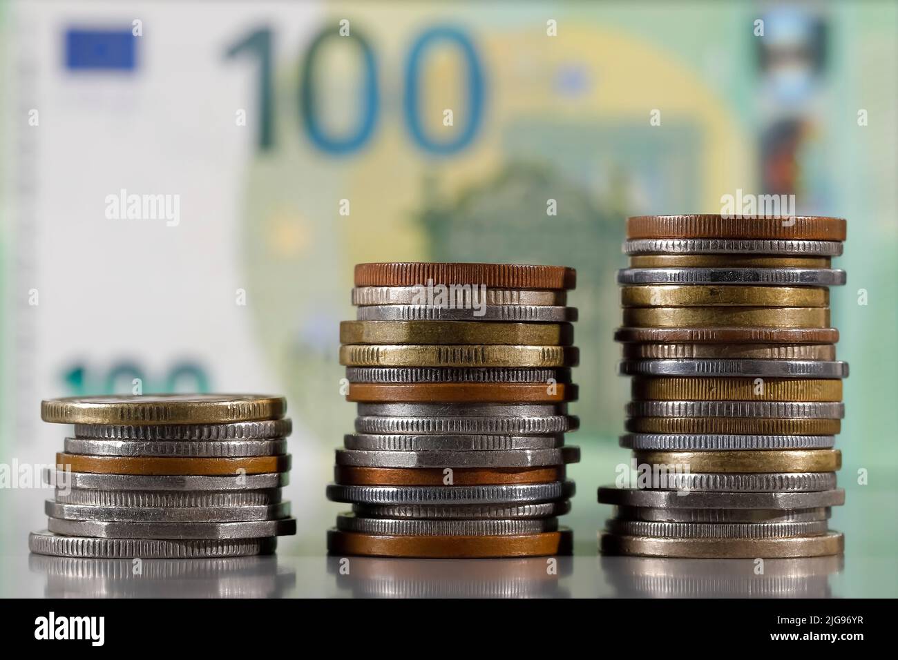 Here are stacked various coins and are shown against denomination of the euro banknote background. Stock Photo
