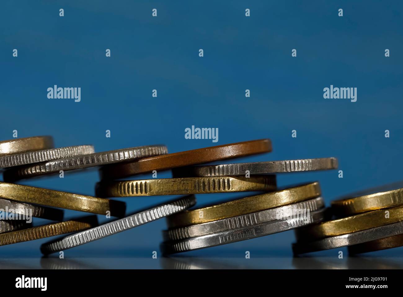 Different coins are arranged and are shown against blue background. Stock Photo