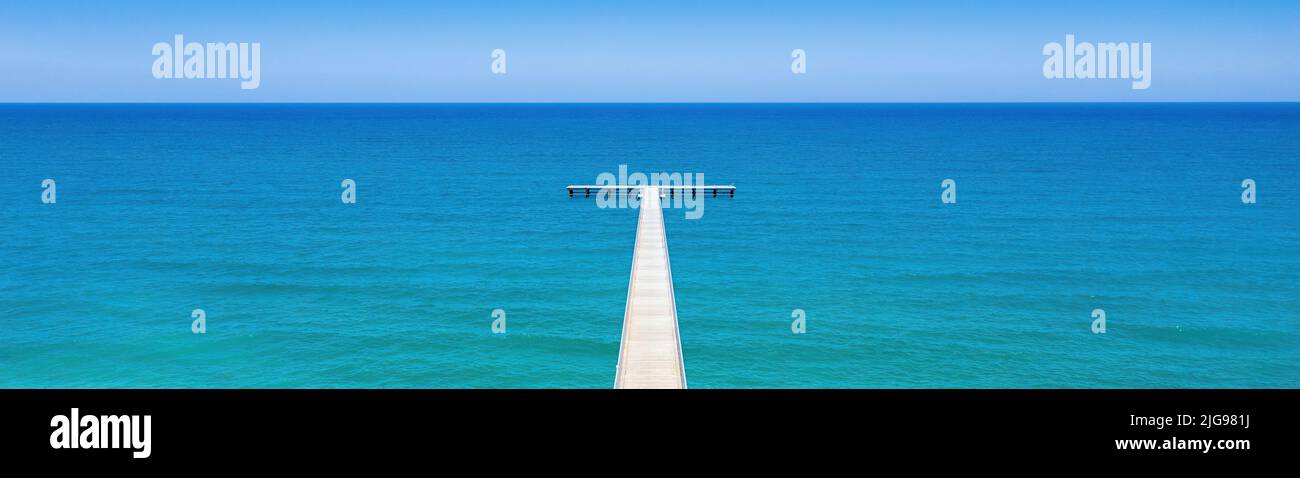 White wooden pier out to blue sea. Seascape panorama from above, horizon over water Stock Photo