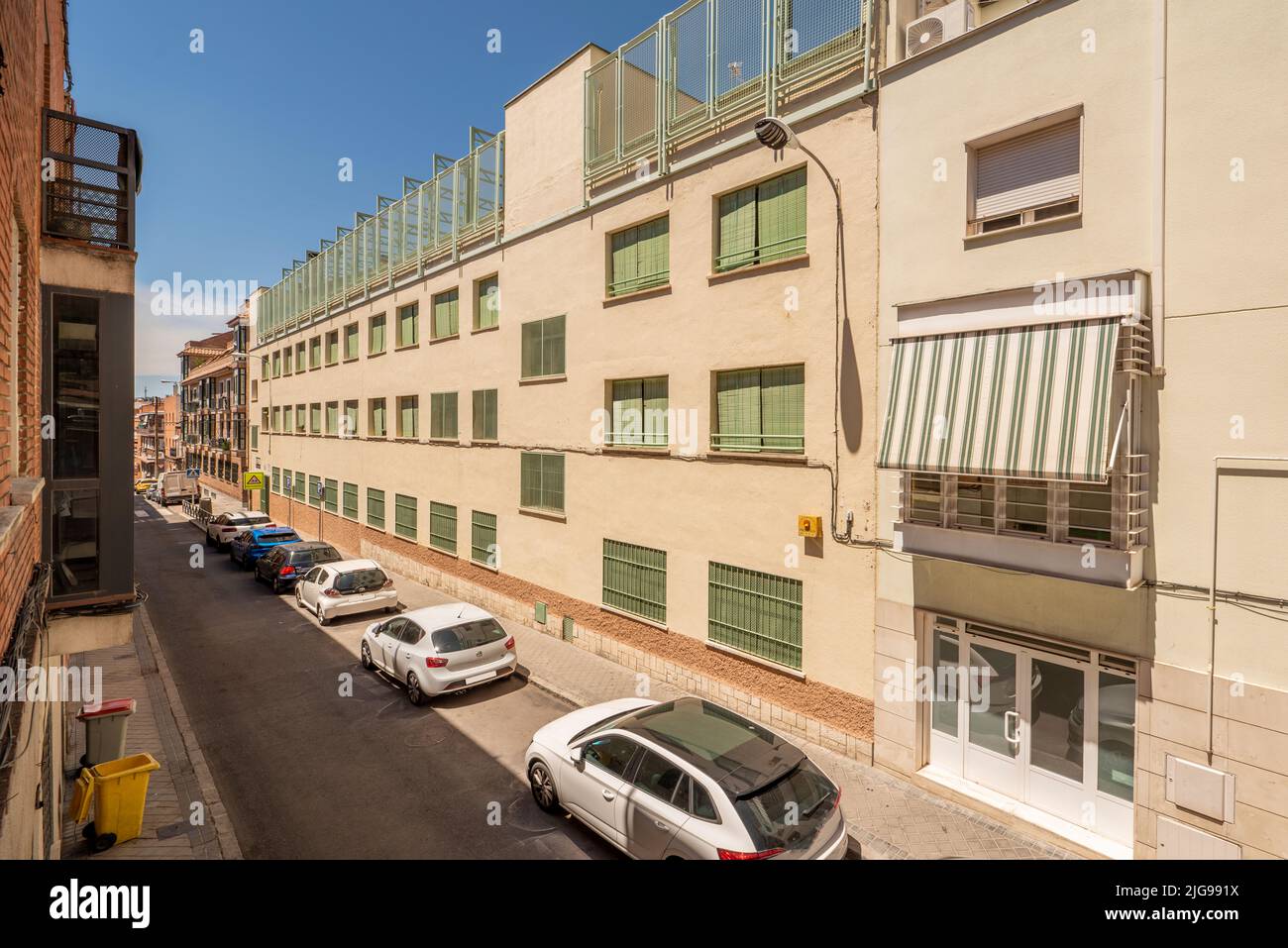 Facade residential buildings in a narrow street full of parked cars Stock Photo