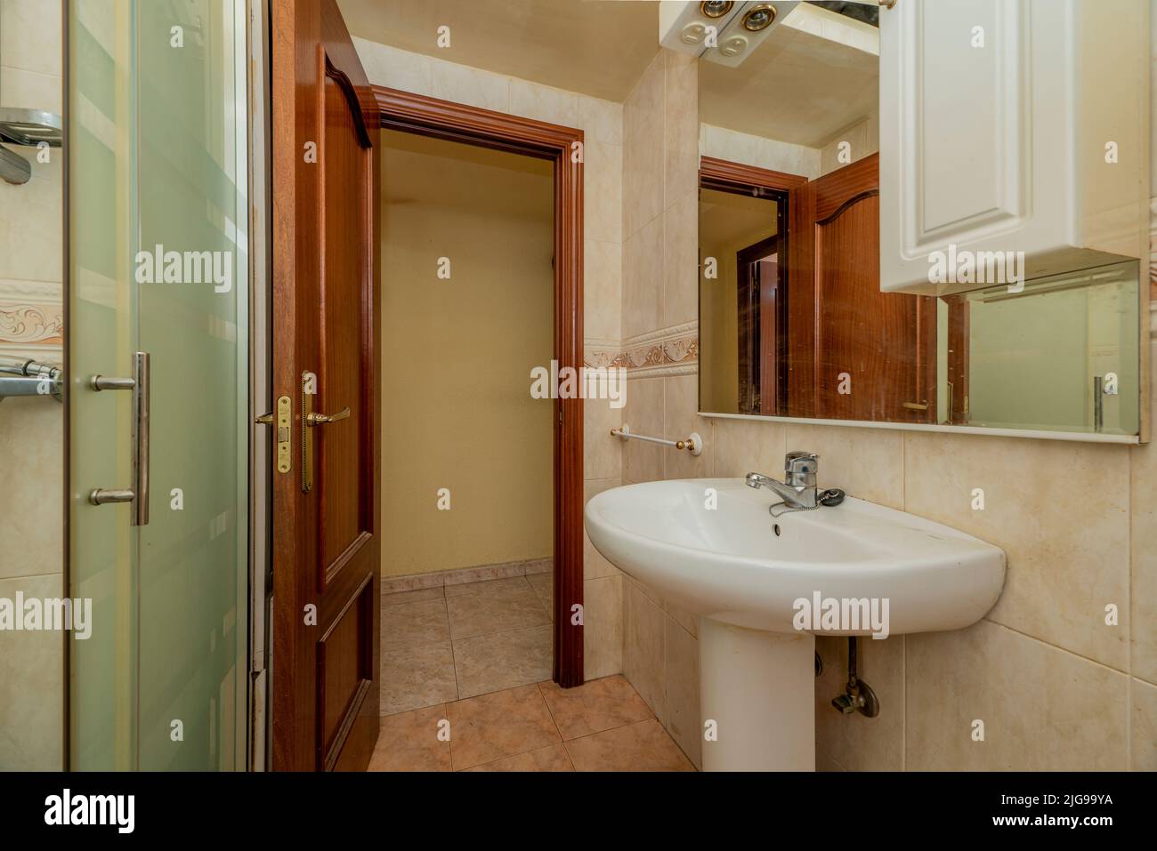 Bathroom with white woodframed mirror, glassenclosed shower stall and