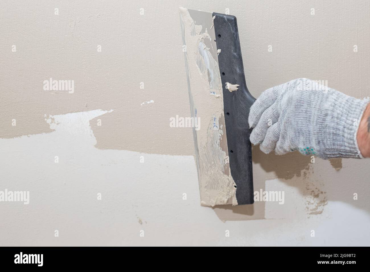 Man plastering wall with puttyknife. Fixing wall surface and