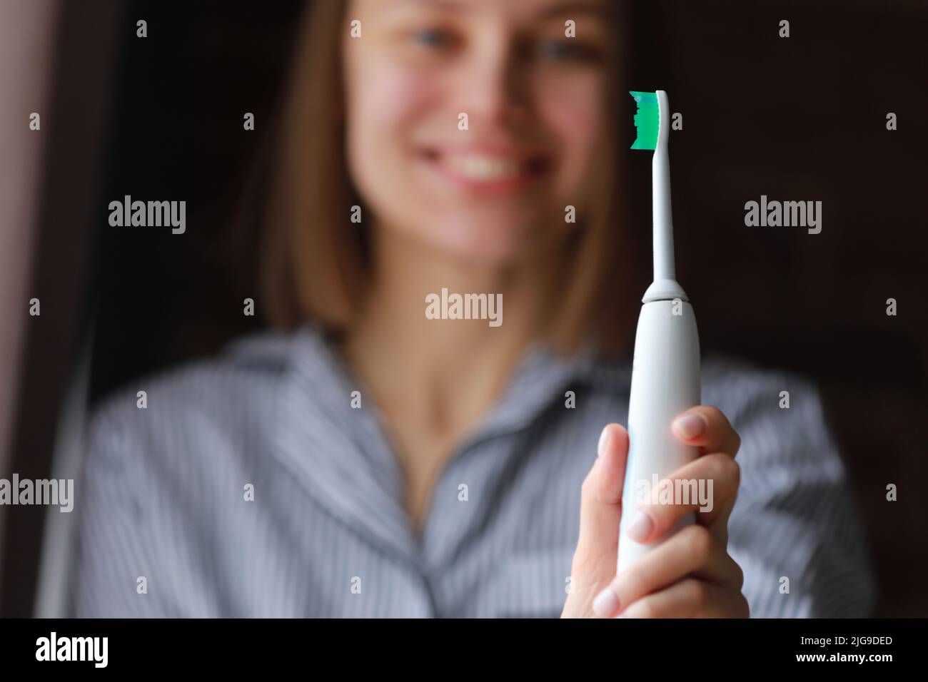 Happy healthy smiling woman with ultrasonic electric brush in bathroom