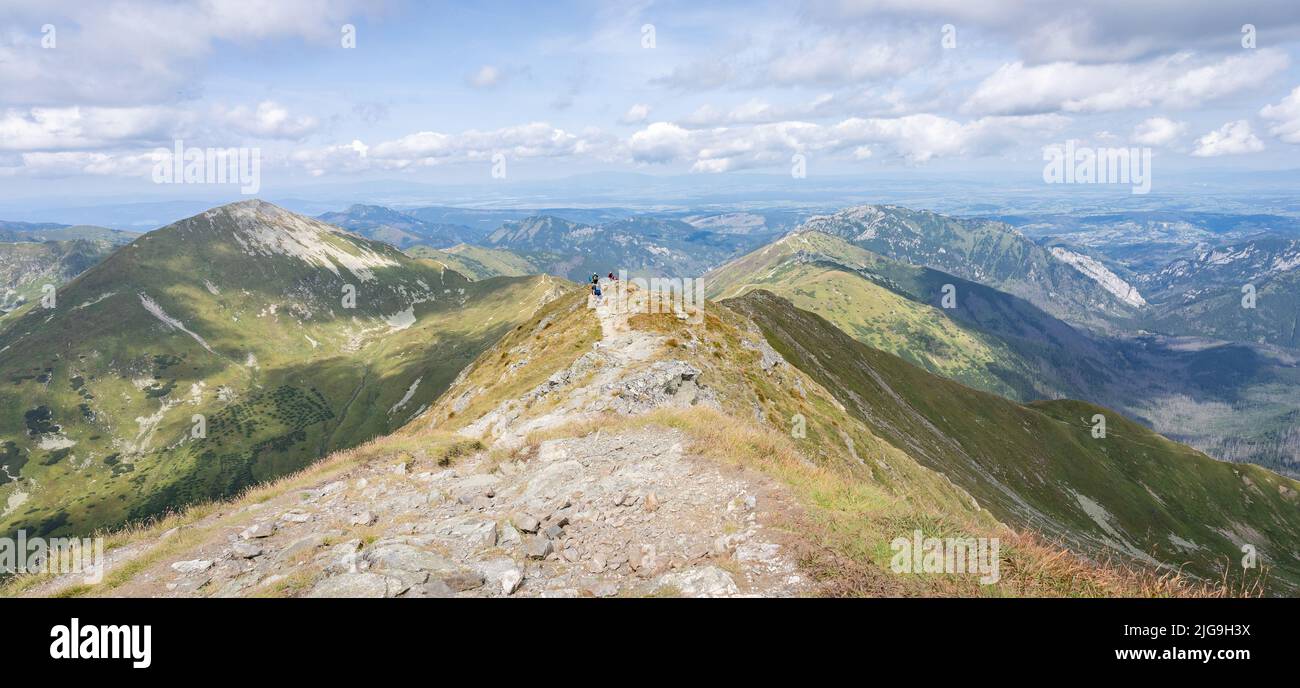 Alpine panorama with mountain ranges and hiker going through them on a sunny day, Slovakia, Europe Stock Photo