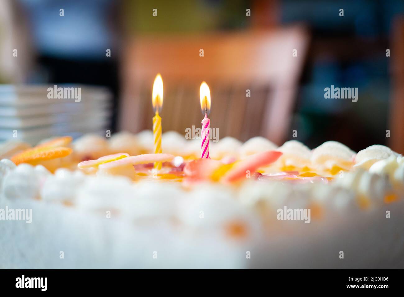 Colourful birthday cake detail with two lit candles Stock Photo - Alamy