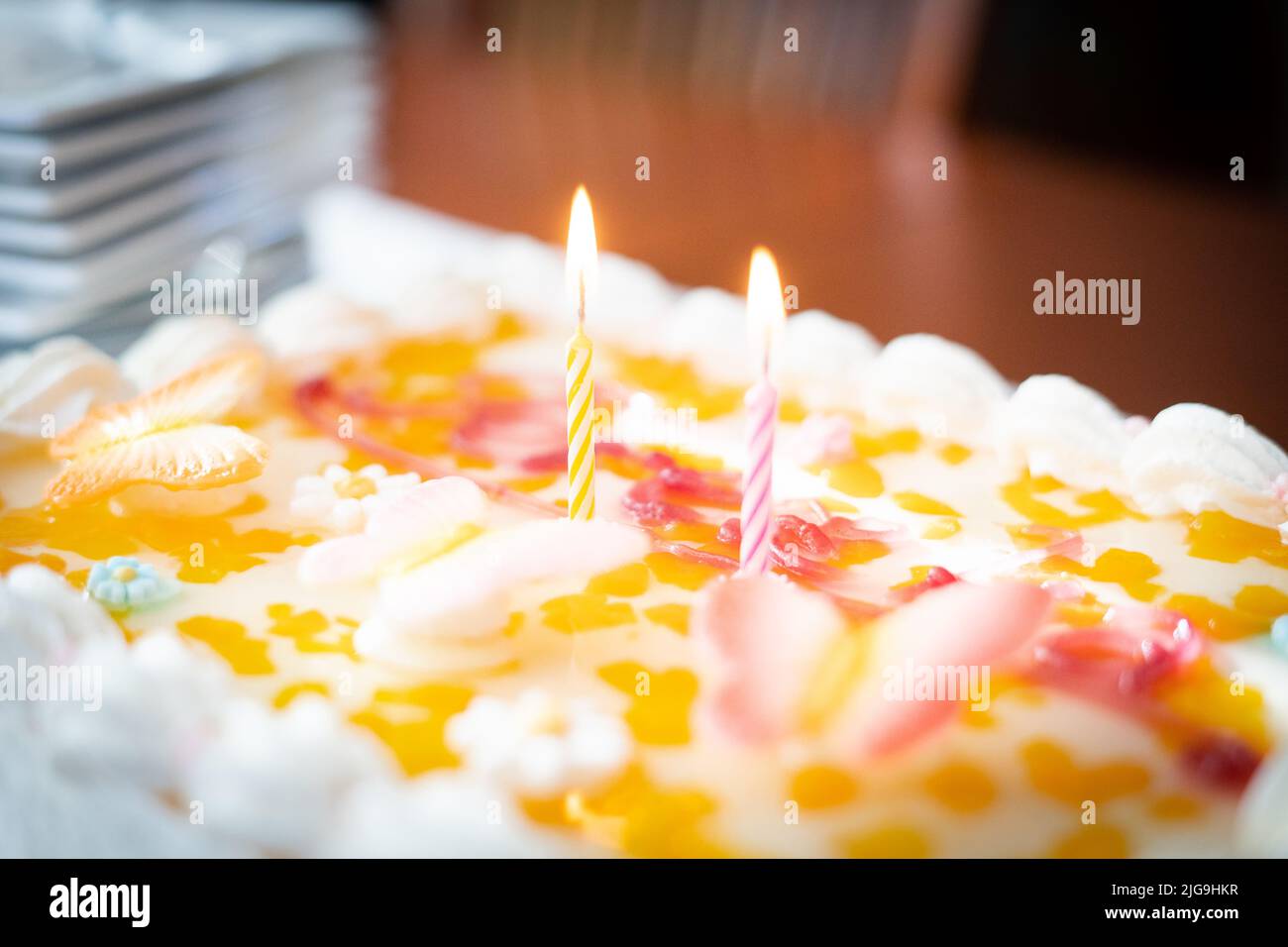 Colourful birthday cake detail with two lit candles, perspective Stock ...