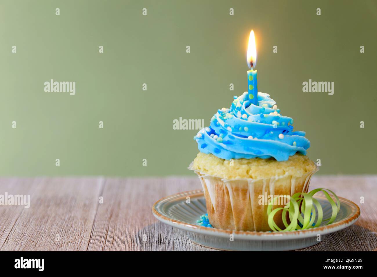 Vanilla cupcake with blue frosting and a blue candle celebrating a Birthday Stock Photo