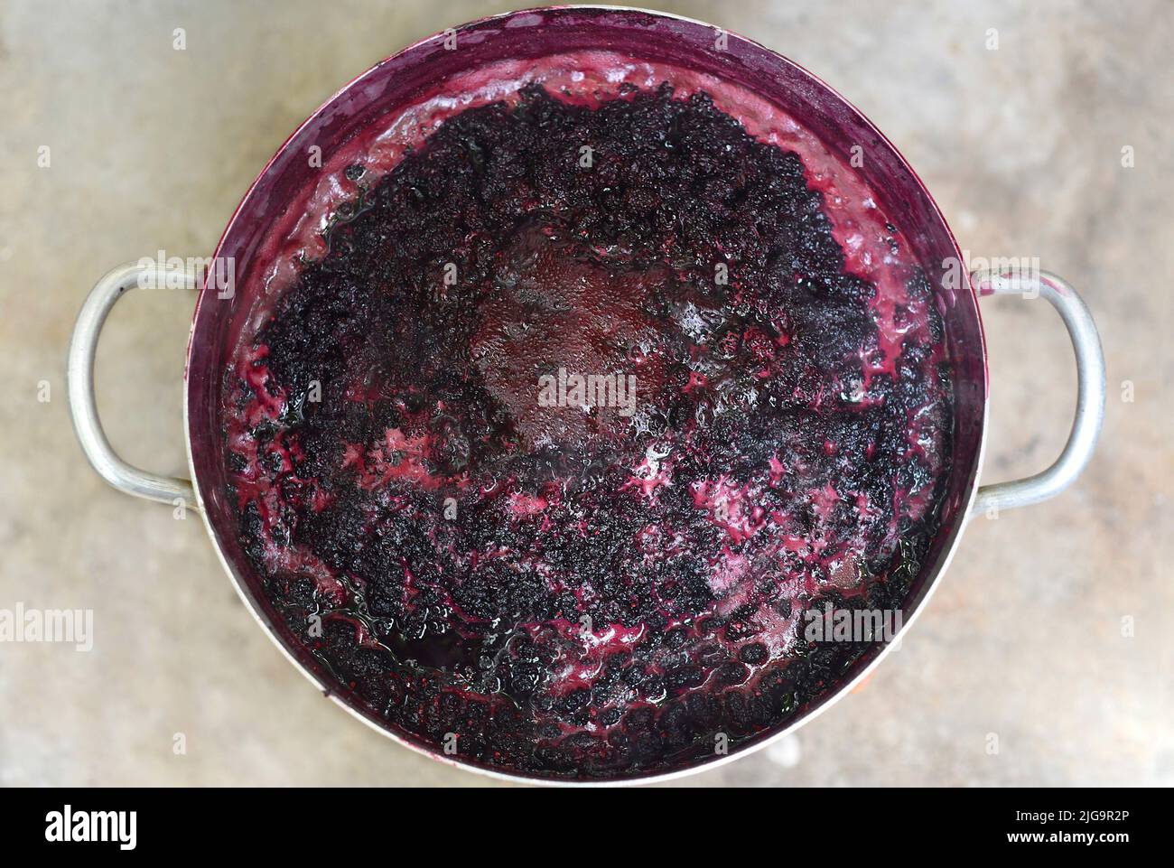 Boiling mulberry jam in a metal saucepan on open fire Stock Photo