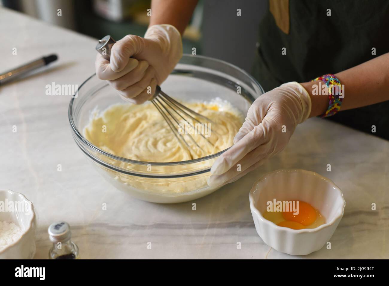 A hands in rubber gloves stirring  dough for a cake Stock Photo