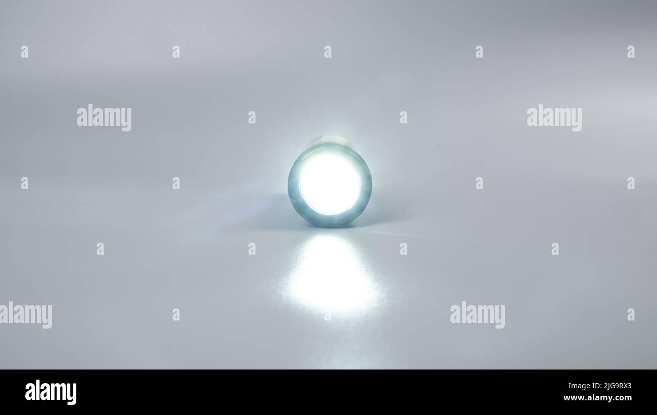 led flashlight on gray background, travel light source. Stock Photo