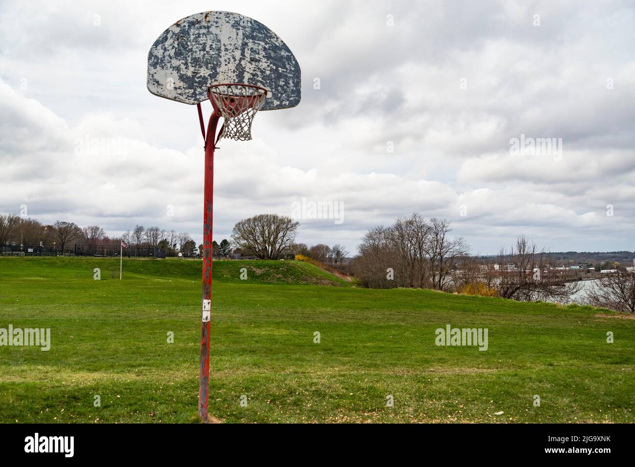 Old outdoor baskeball hoop with the broken wooden backboard in a park in Portland Maine, USA Stock Photo