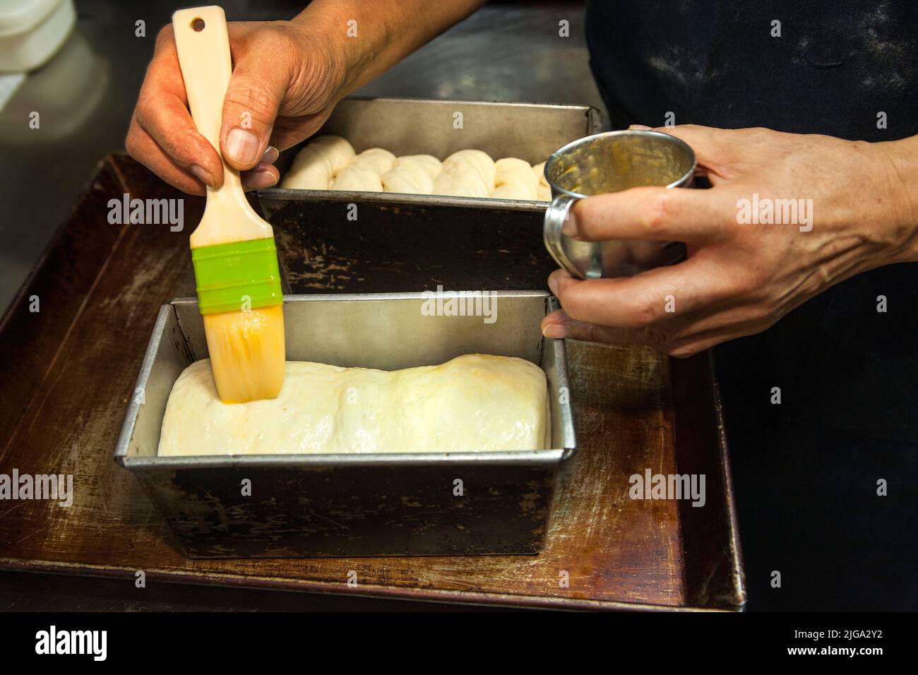 Baker applies butter to bread dough in Nakaikegami, Tokyo, Japan Stock Photo