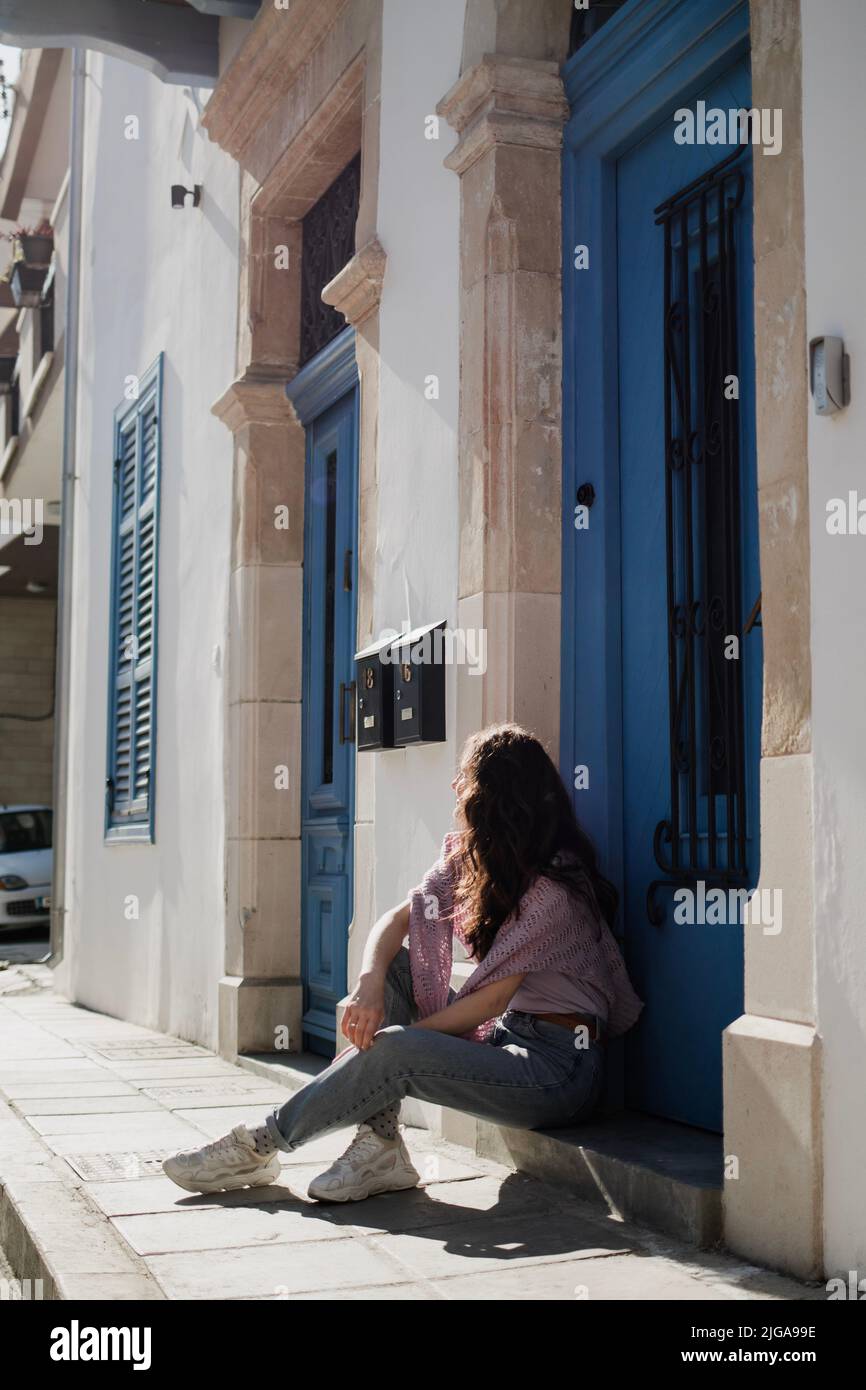 Woman is sitting near beautiful building with blue doors in Larnaca, Cyprus Stock Photo