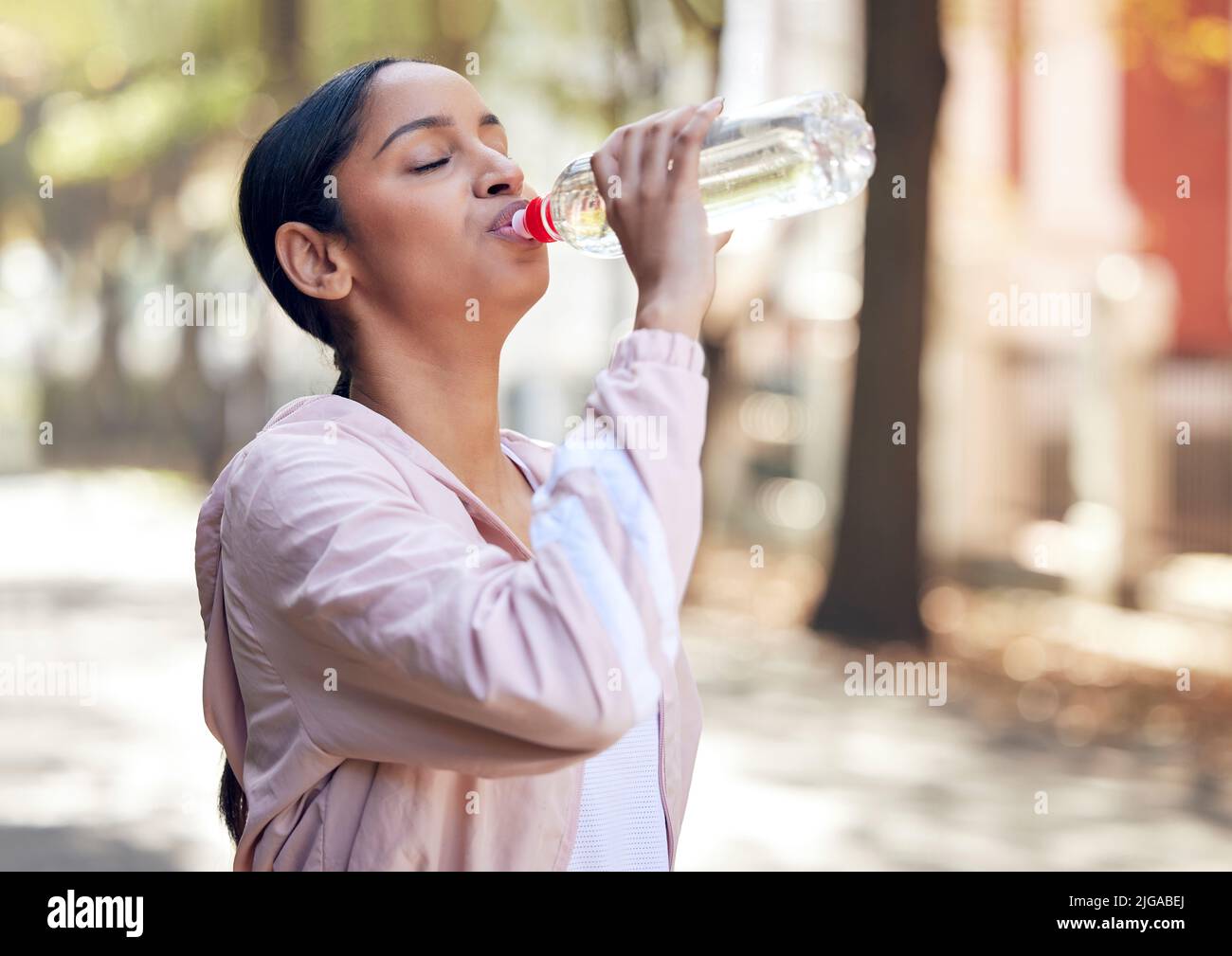 Quenching her thirst before she continues. a sporty young woman