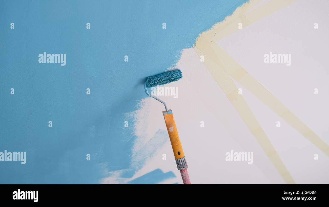 Decorator painting wall in blue color and using scotch tape Stock Photo