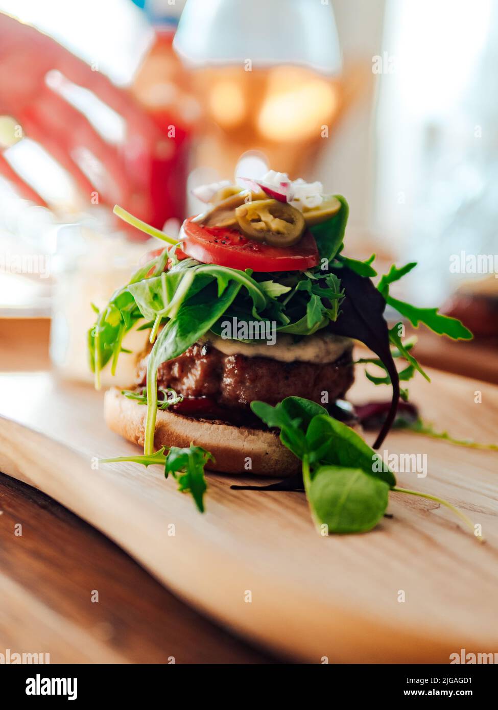 A yummy burger with meat, salad and other ingredients on a wooden surface Stock Photo
