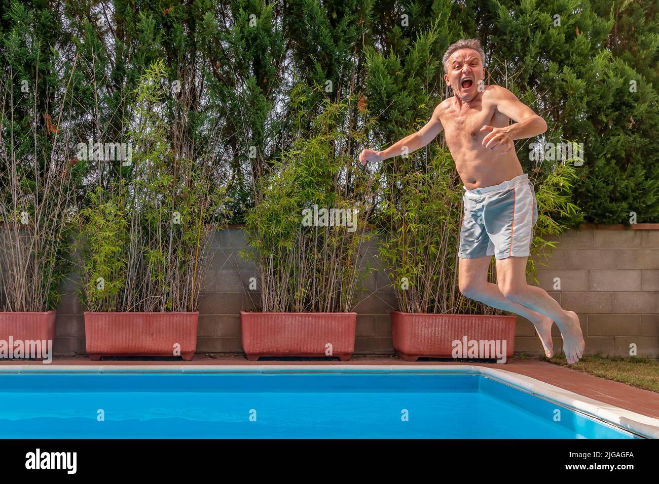 A middleaged white man dives into the pool making a very funny