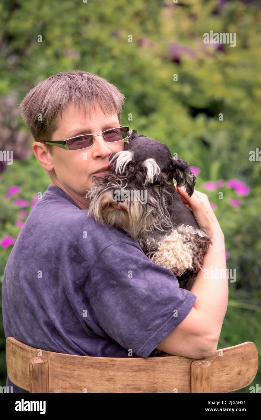 Woman with her miniature schnauzer dog sitting outdoor Stock Photo