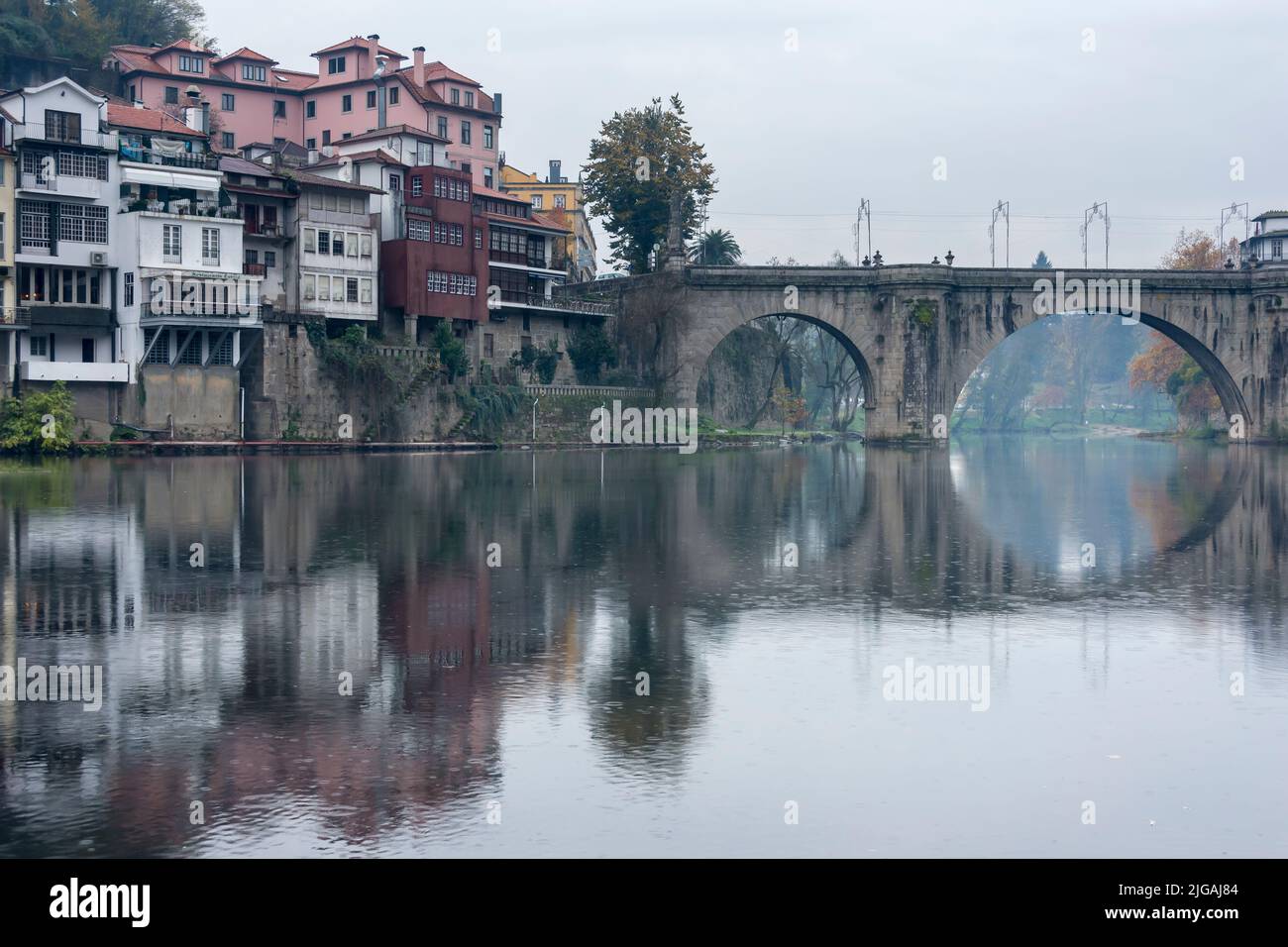 Overhang homes and arch bridge along the Tamega river in Amarante, Portugal. Stock Photo