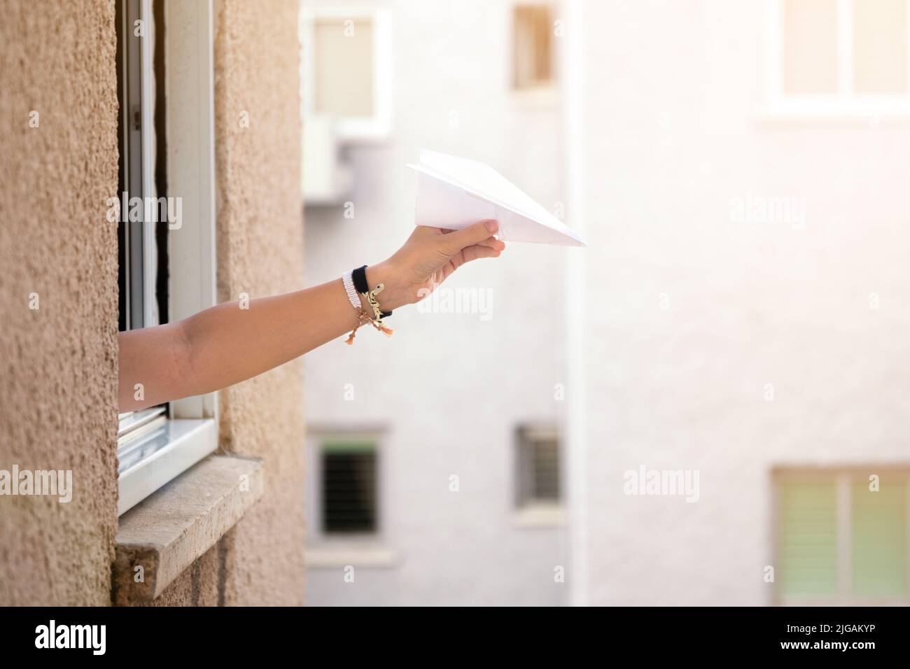 Hand of a teenage girl launches a paper plane from the window Stock Photo