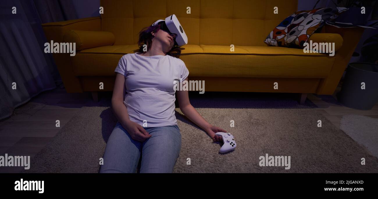 Woman played a lot of games and got tired, fell asleep sitting on floor in vr headset and with joystick in her hand. Concept of gambling addiction of Stock Photo